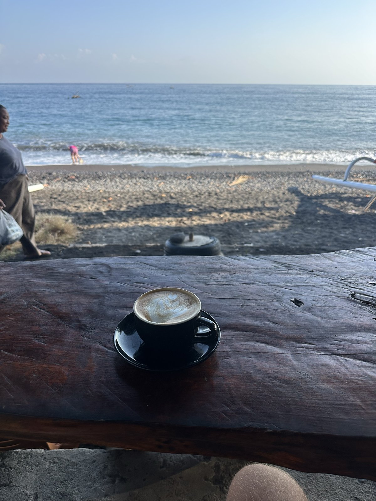 Cappuccino sur une table en bois face à la plage d'Amed