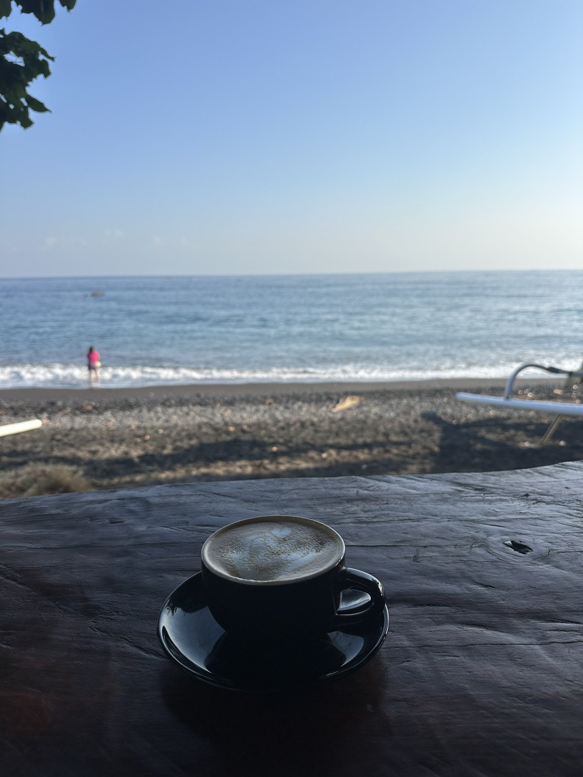 Tasse de café sur la table en bois de la terrasse, vue sur la plage d'Amed