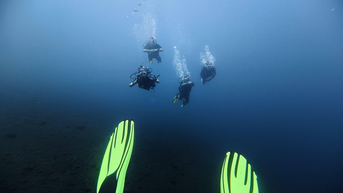 Groupe de plongeurs en Open Water sous l'eau à Amed, un plongeur fait un signe de la main